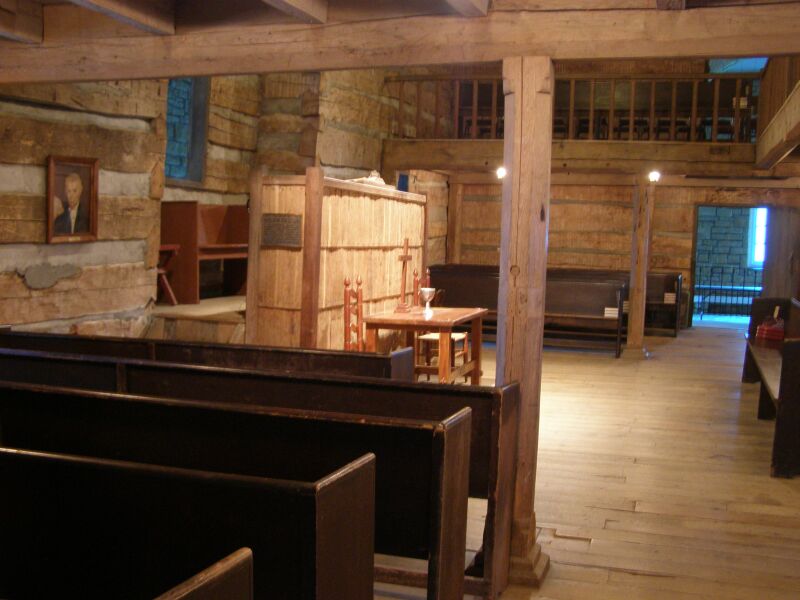 Interior of the Cane Ridge Meeting House with exposed log walls and pews.
